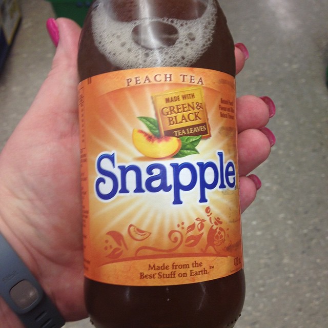 a person holding a glass bottle of snapple juice