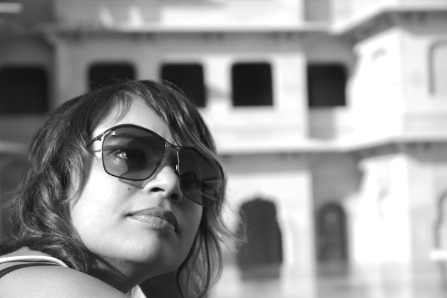 woman in sunglasses posing in front of large building