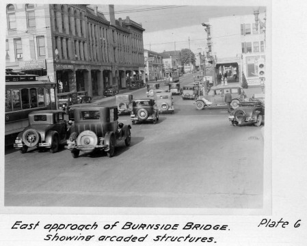 black and white pograph of old cars driving down a street