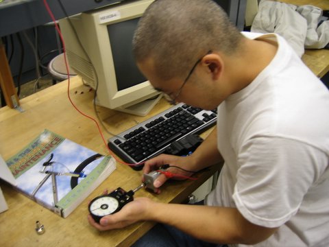 a man holding a small compass sitting next to a computer keyboard
