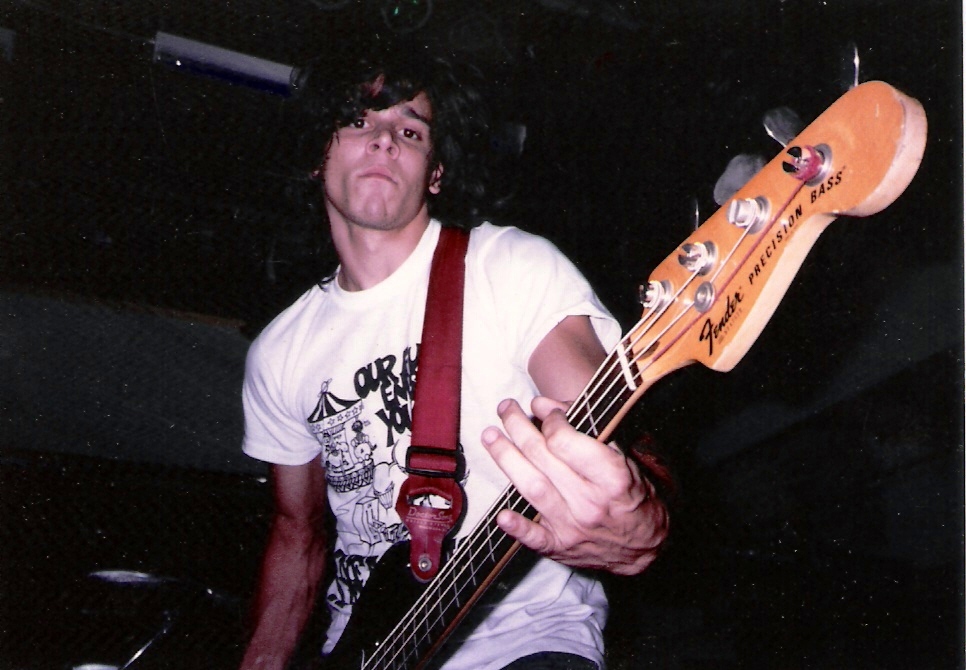 a man playing guitar while wearing a white shirt