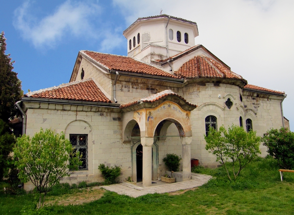 an old church building is surrounded by lush green trees and a white sky