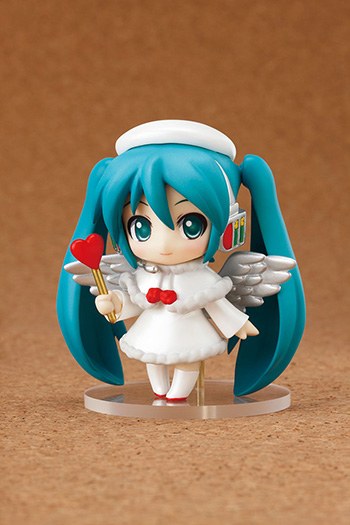 an anime figure in a white dress and blue hair, standing next to a little figurine