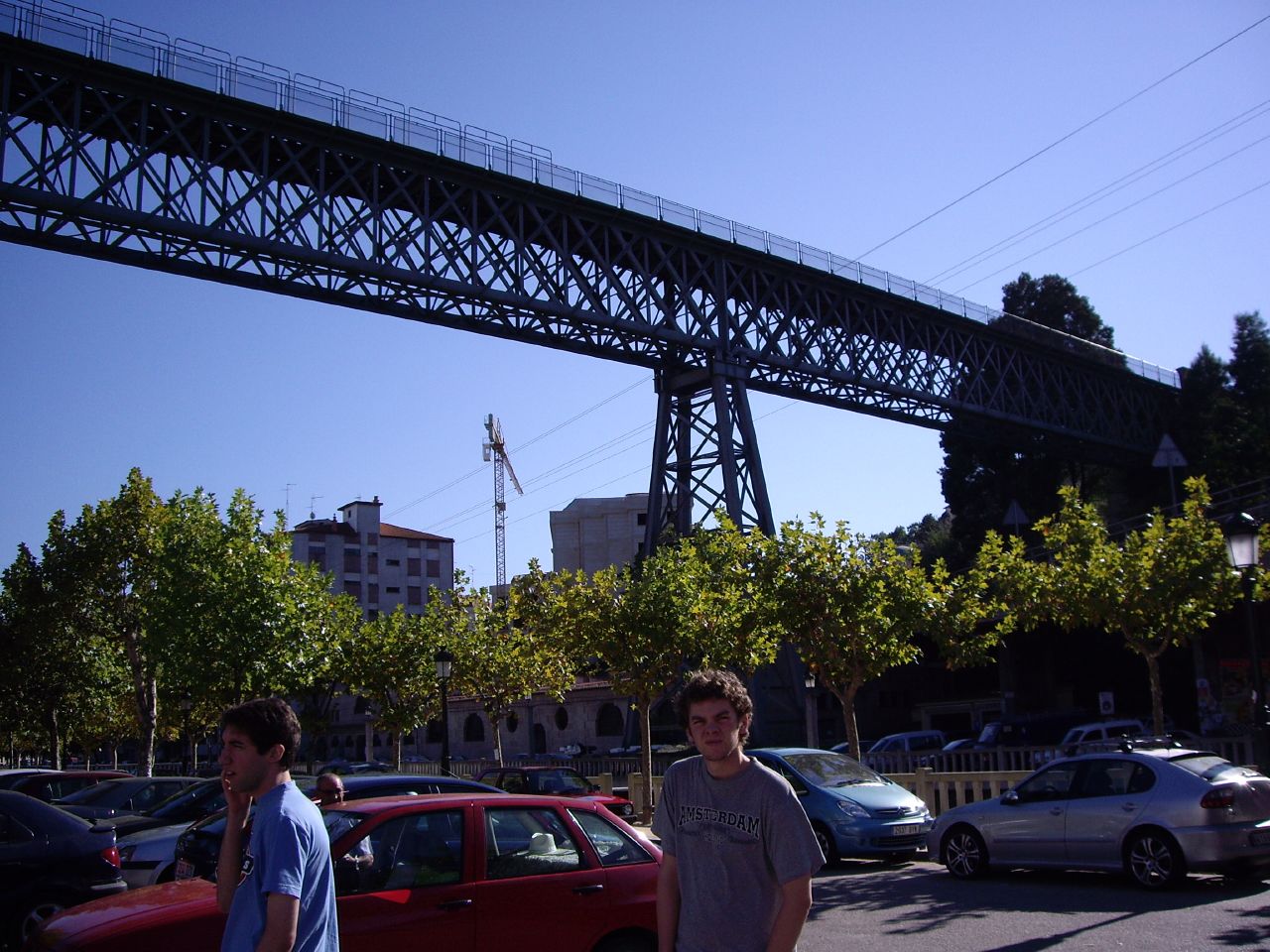 two boys walk under an overpass with cars