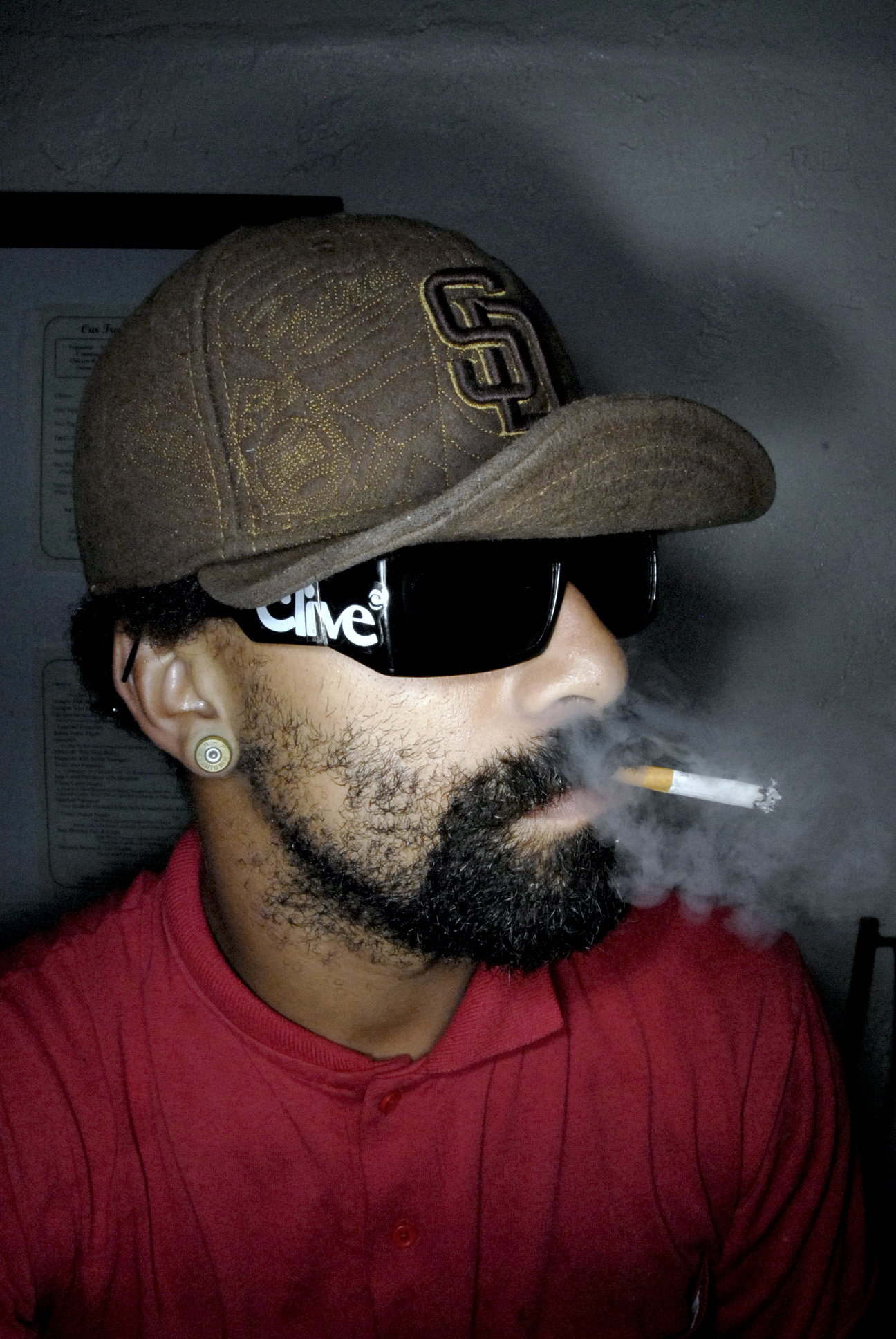 a man wearing sunglasses and a hat smoking a cigarette
