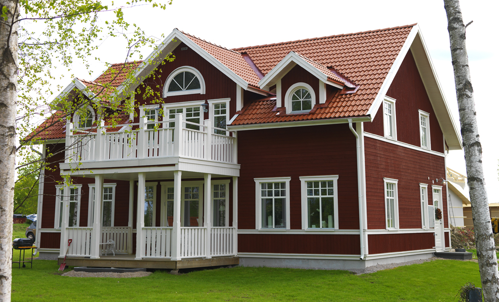 a red house sitting on top of a lush green hillside