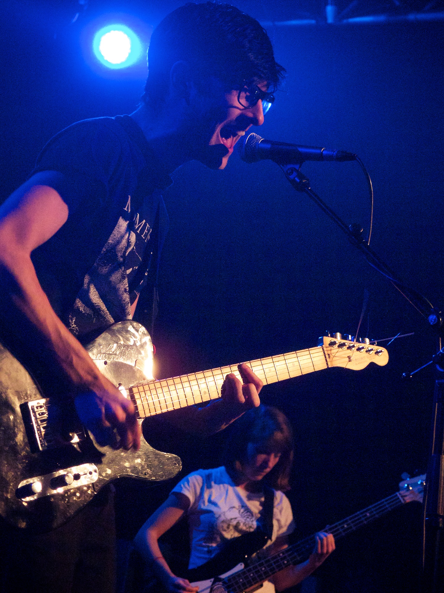 man playing electric guitar while woman sings in the background