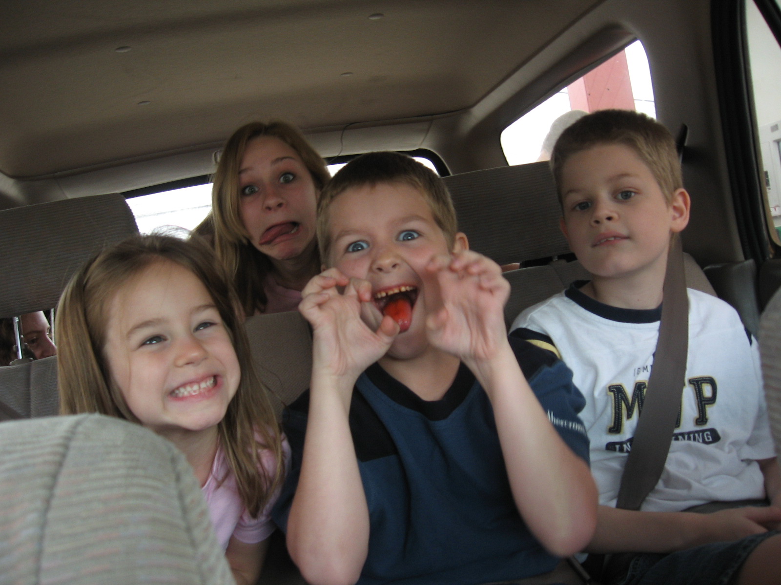 some little boys and girls that are on the back of a car