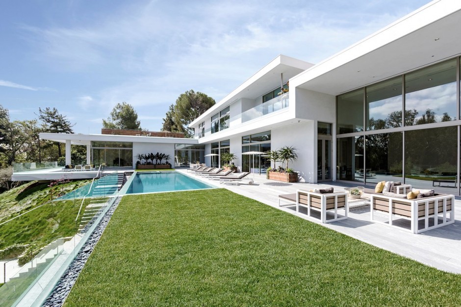 a pool is surrounded by large windows and lawn furniture