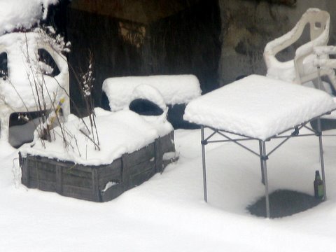 a pile of snow covered tables next to a building