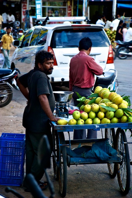an vendor standing near his cart with fruit