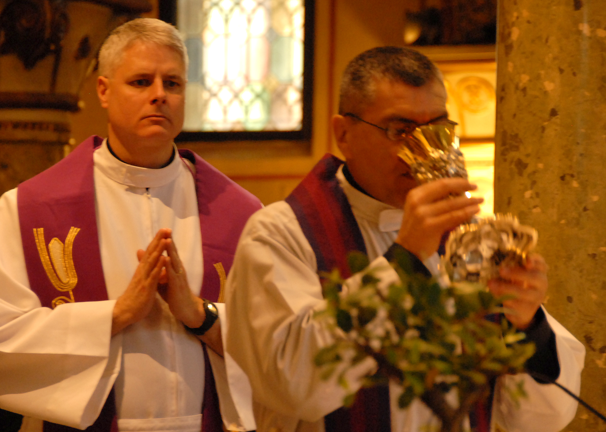 two priests giving each other some chalicee and candles