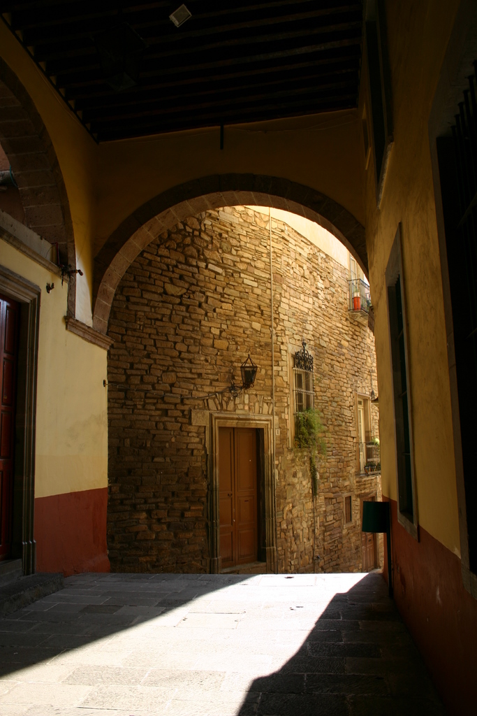 an arch and doorway with two doors in a brick building