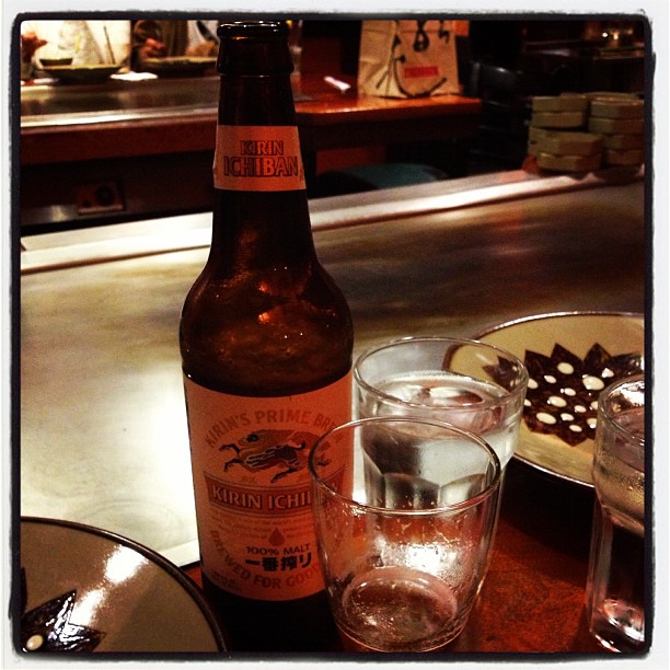 an empty beer bottle sits on a table with empty glasses