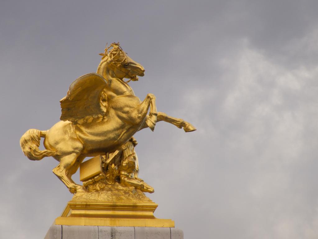 the gold statue is situated in front of a cloudy sky