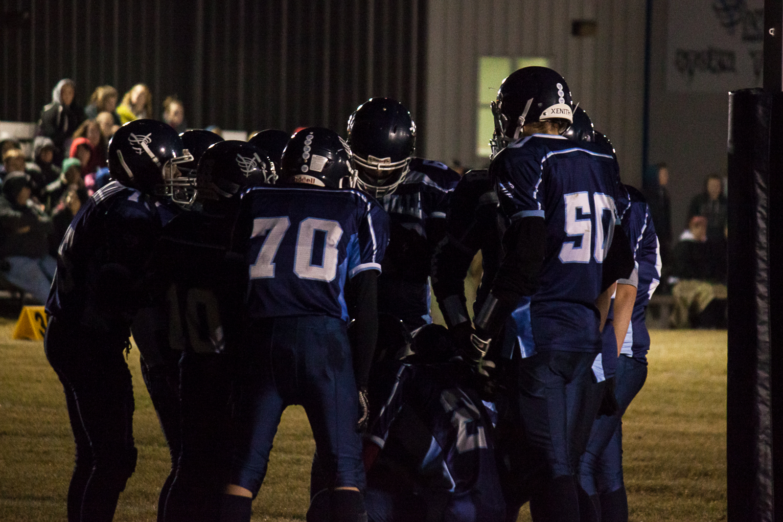 football players huddle together at night during a game