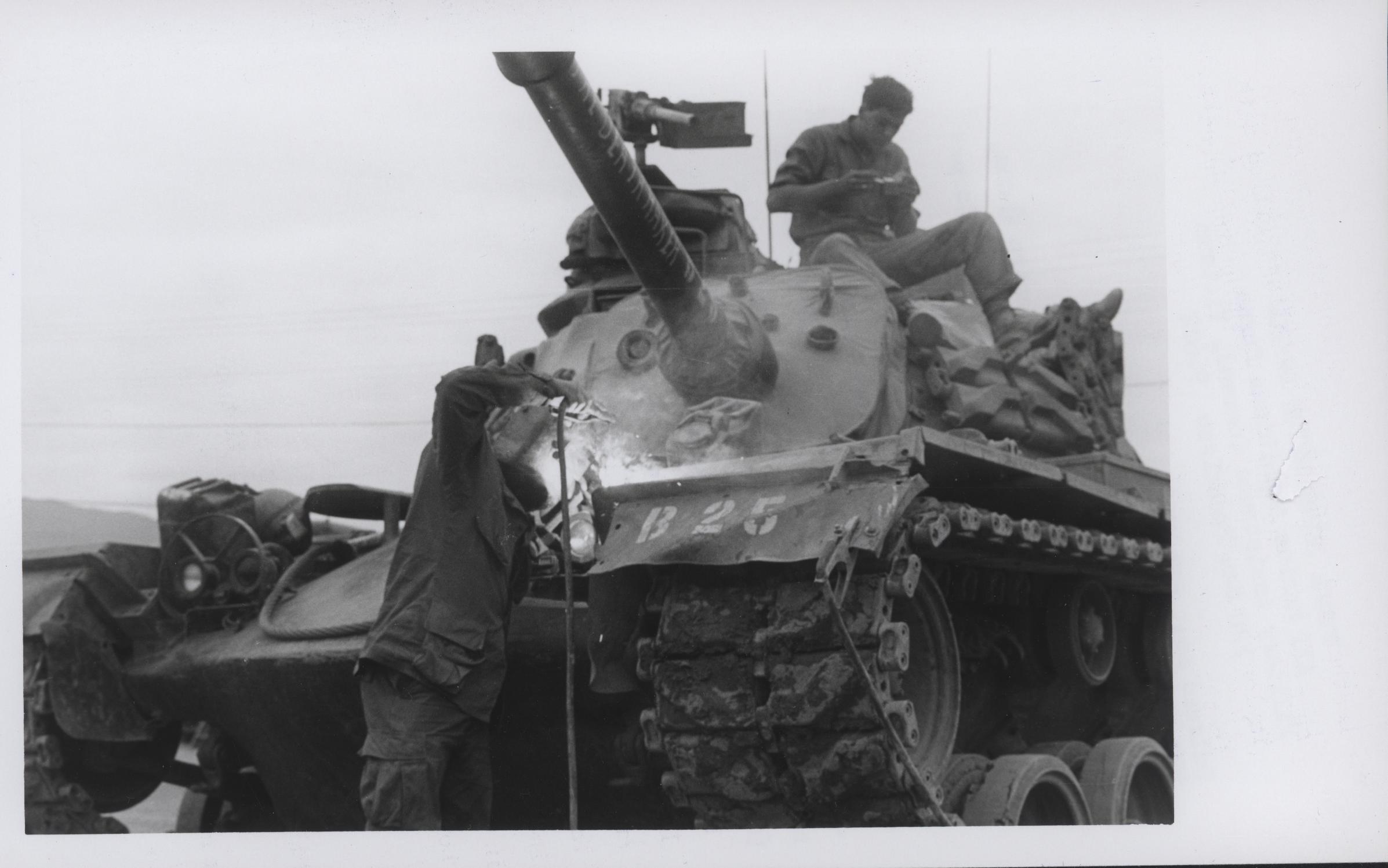 soldiers standing on top of an unloading tank