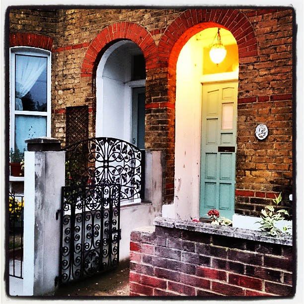 an old brick house with a gate and light