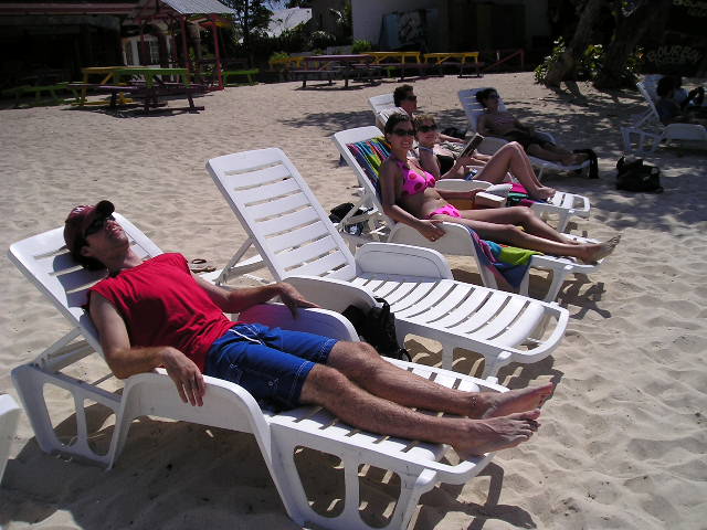 some people sitting on chairs and loungers in the sand