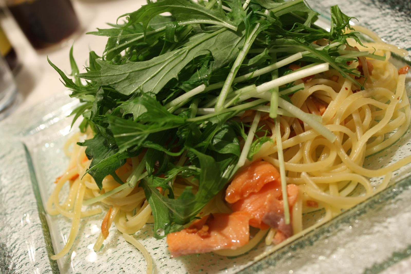 closeup of pasta with salmon and parsley on glass plate