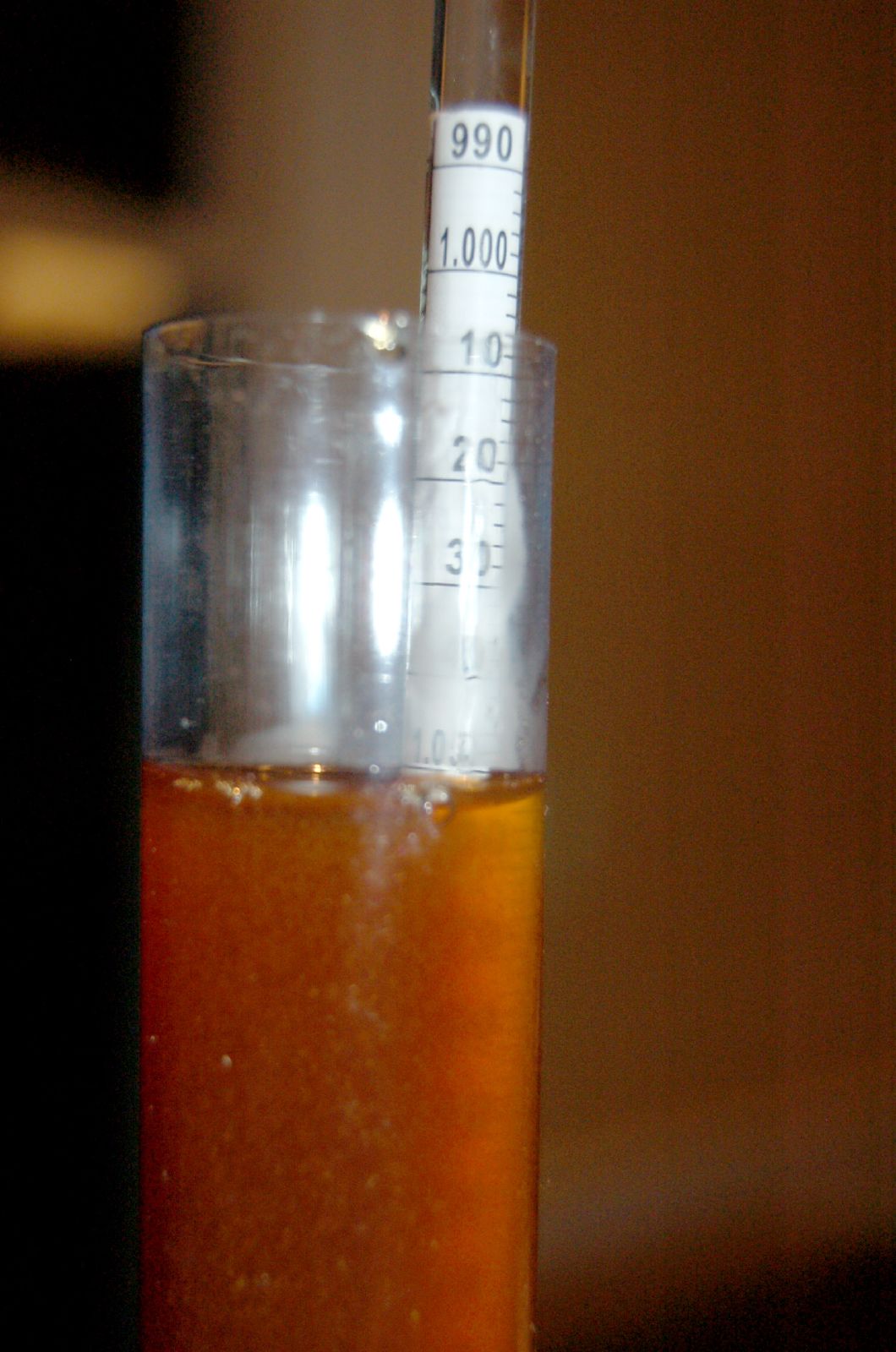 a measuring stick sticking out of a tall glass filled with liquid