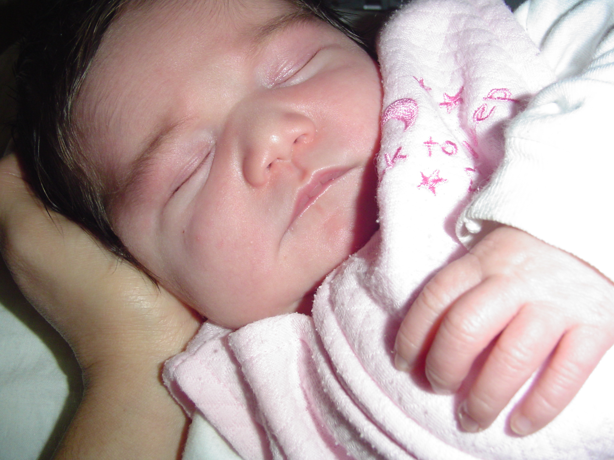 a baby sleeps in the arms of her mom