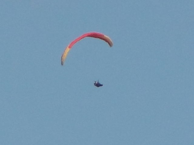a person para - sailing in the middle of a blue sky