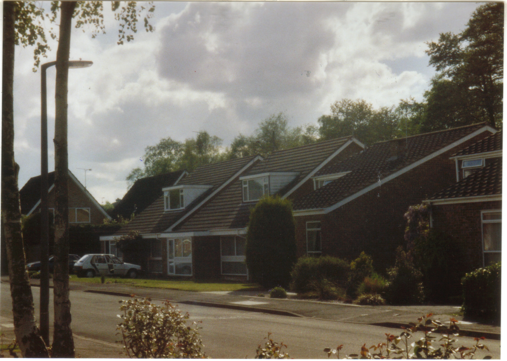 a number of houses behind a street with bushes in front of it