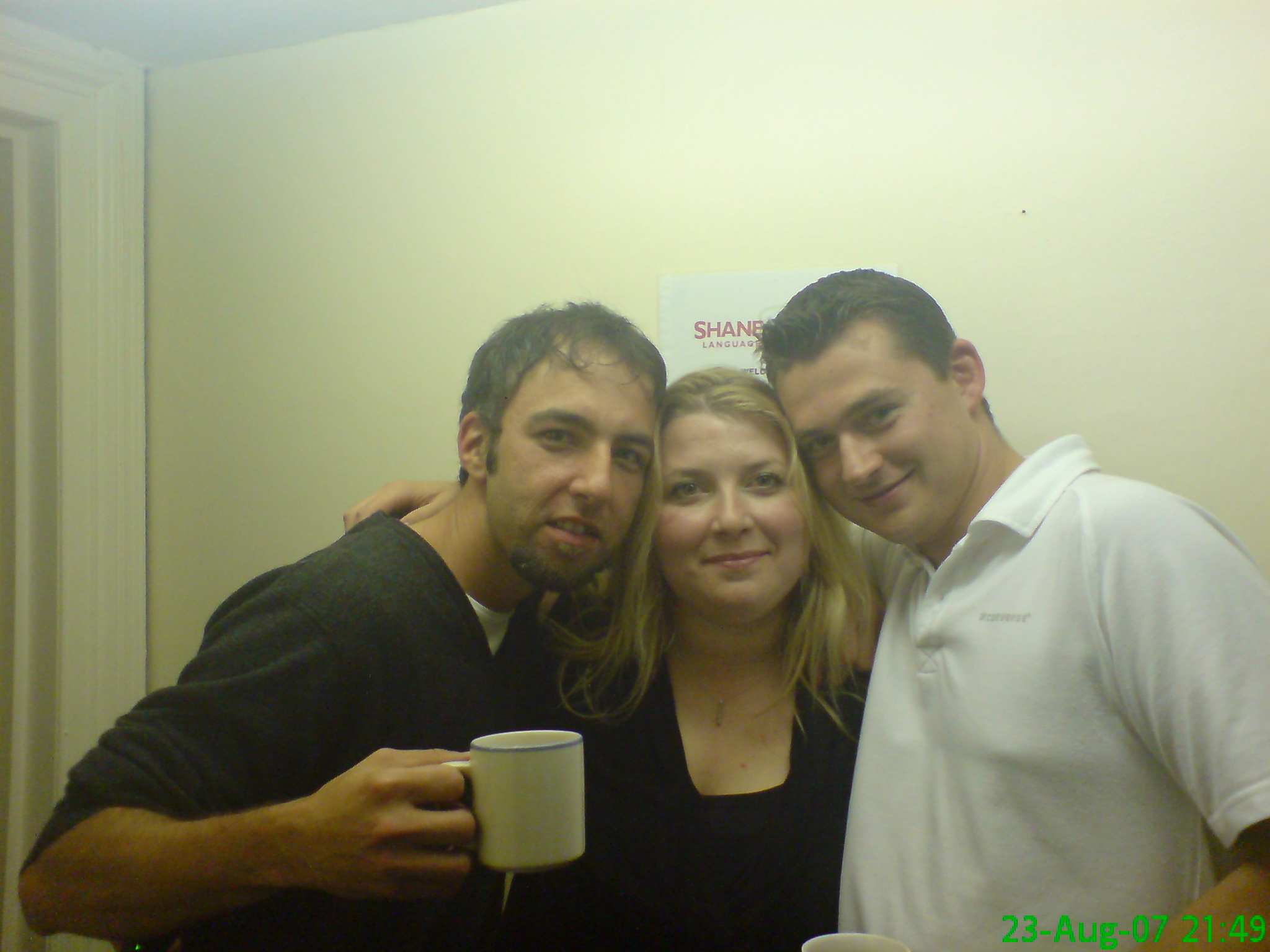 three people holding up mugs in the hallway