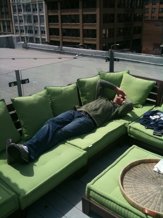 a man laying on a green couch in a city