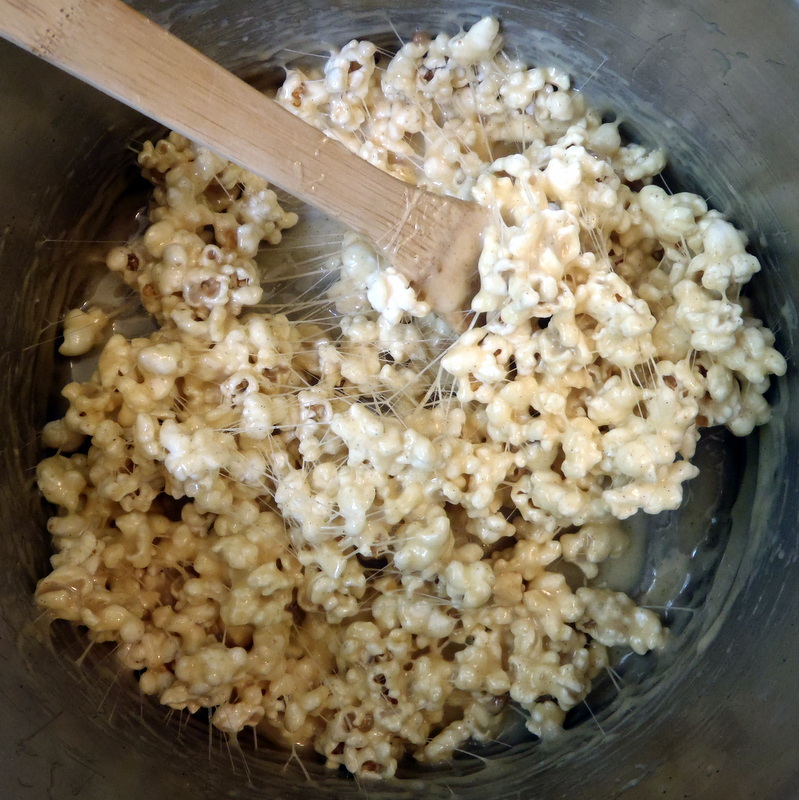 a bowl full of popcorn being cooked with a wooden spoon