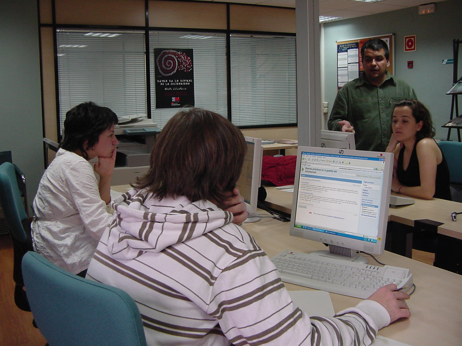 two women and one man sitting at a table looking at a computer screen