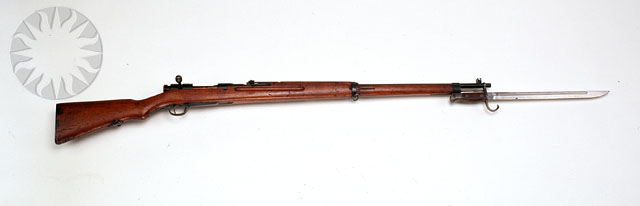 a rifle on display, on a white wall
