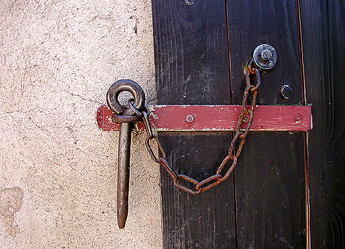 the large iron lock is on a rustic black door
