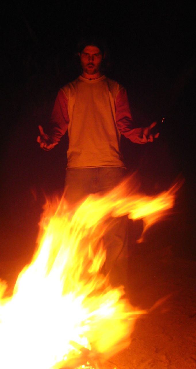 a man standing near a bonfire holding two torches