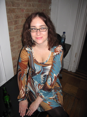 a woman sitting next to a wine glass and a bottle