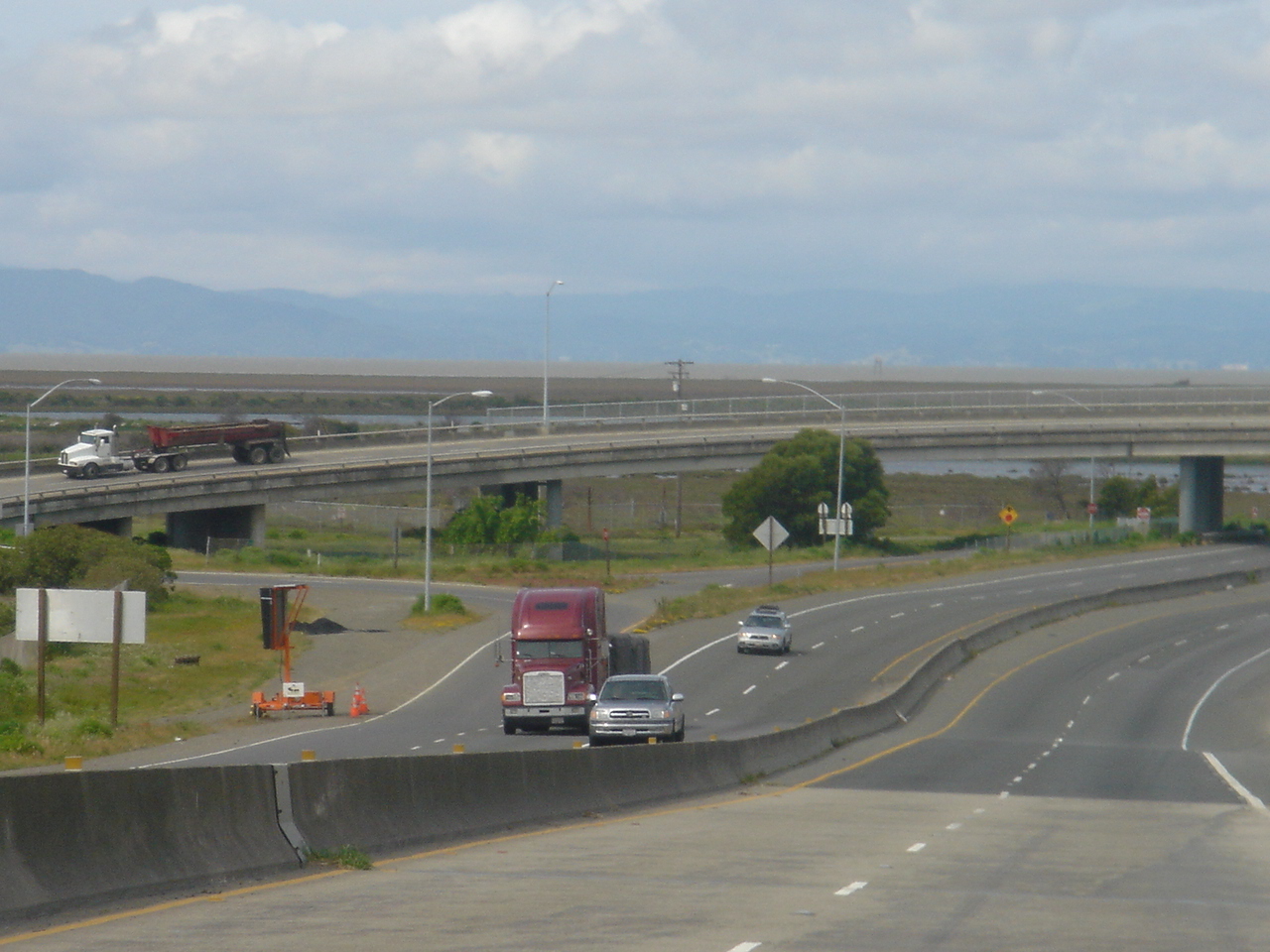 two trucks on a highway near a grassy area