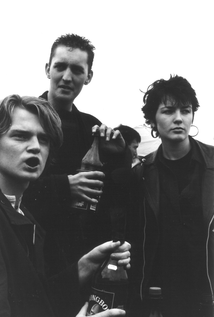 three men pose with a bottle of coke