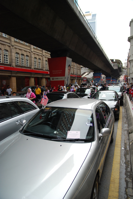 a group of cars parked in a lot near a bridge