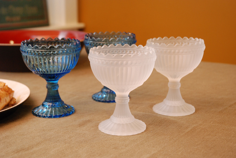 a table with three wine glasses in blue and clear