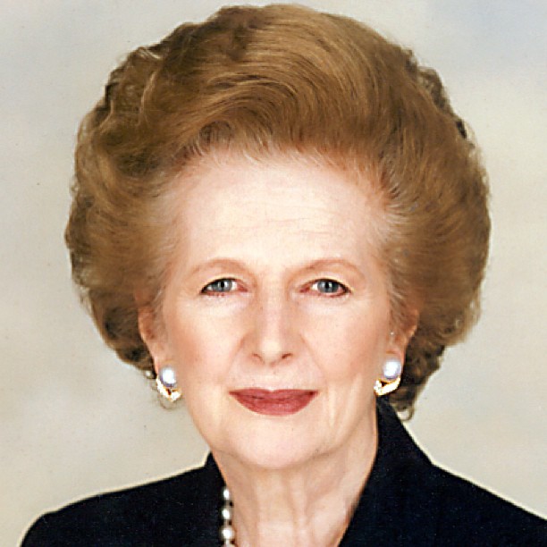 an older woman in a black suit with pearls