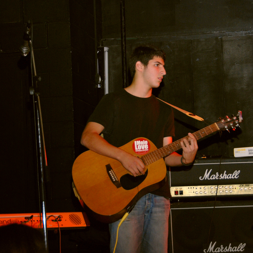 a young man playing an acoustic guitar next to a microphone