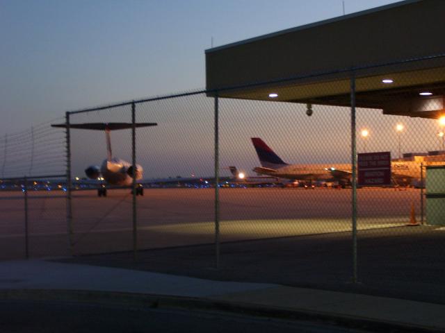 a plane sits behind a fence at an airport