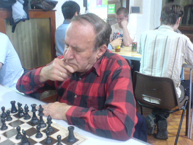 a man sitting at a table with chess set