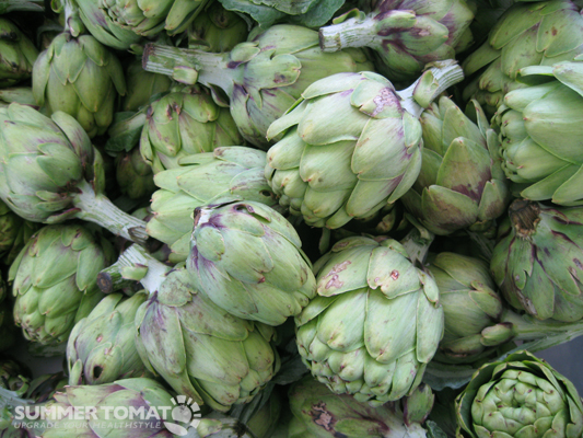 a large group of artichokes are stacked up together