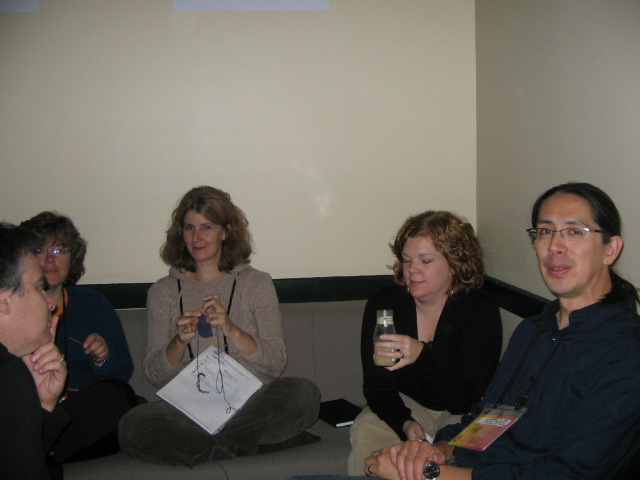 four people sitting on a couch holding cell phones