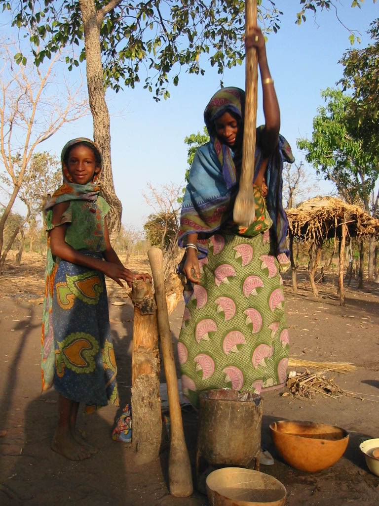 two young women standing next to each other near a tree