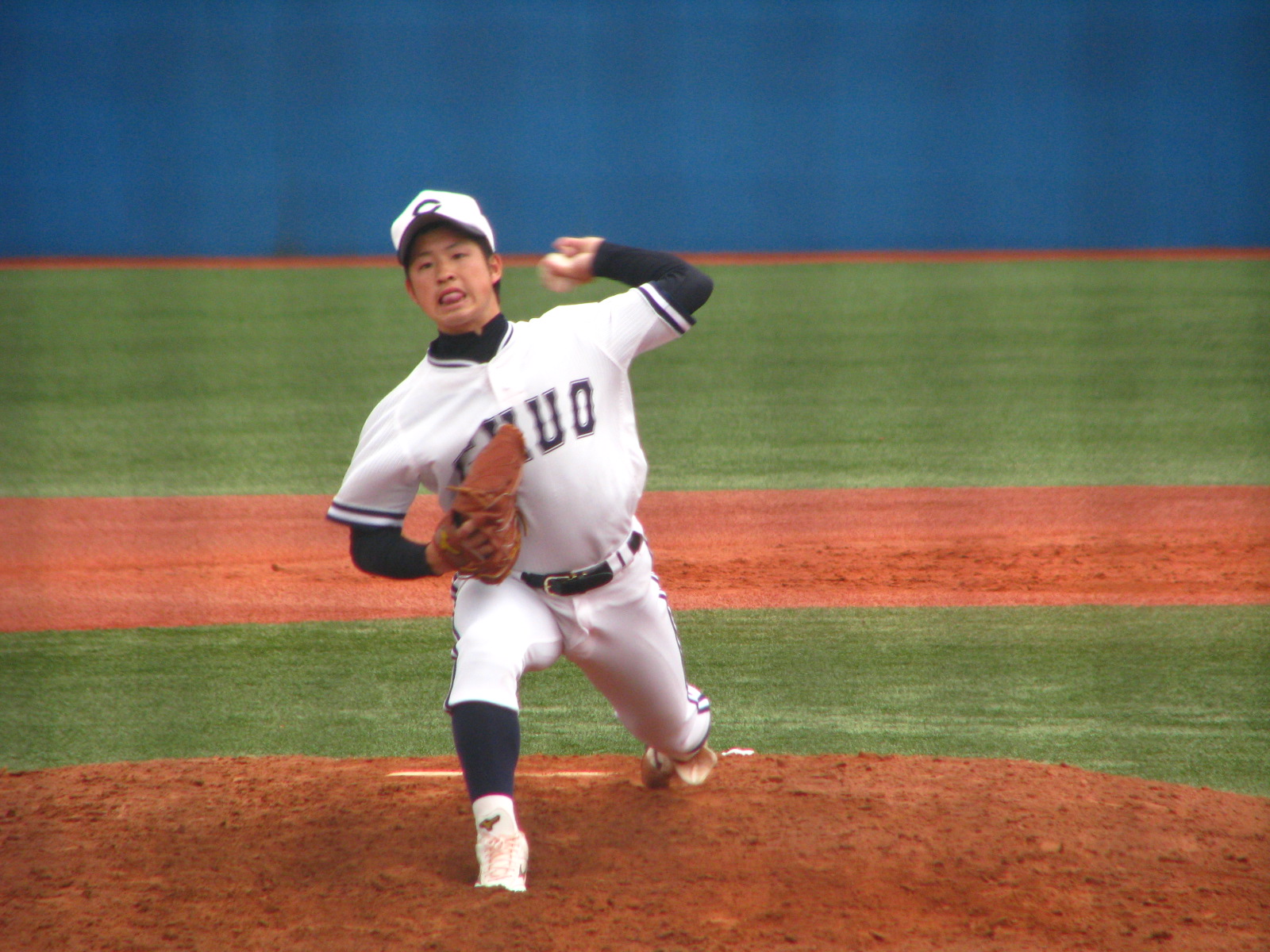 a young baseball player in uniform throws a pitch from the mound