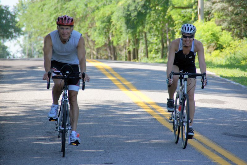 two women riding bikes down a paved road