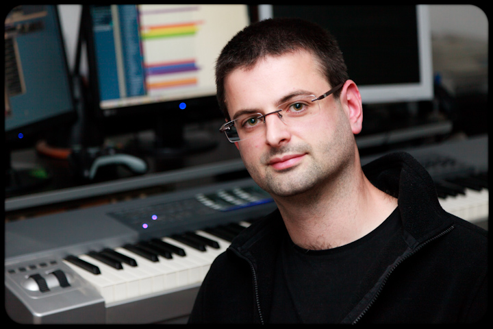 a man wearing glasses with an electric keyboard in the background